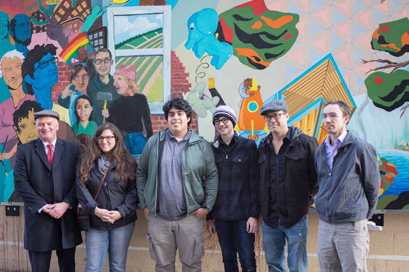 Six people standing in front of a brightly painted mural.