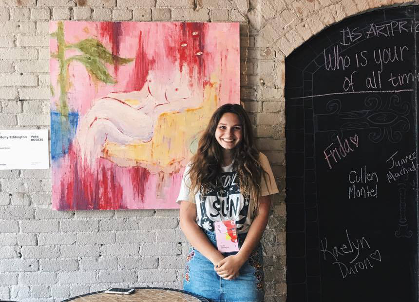 woman standing next to her painting