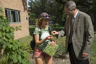 woman holding bag of hops talks to man in glasses