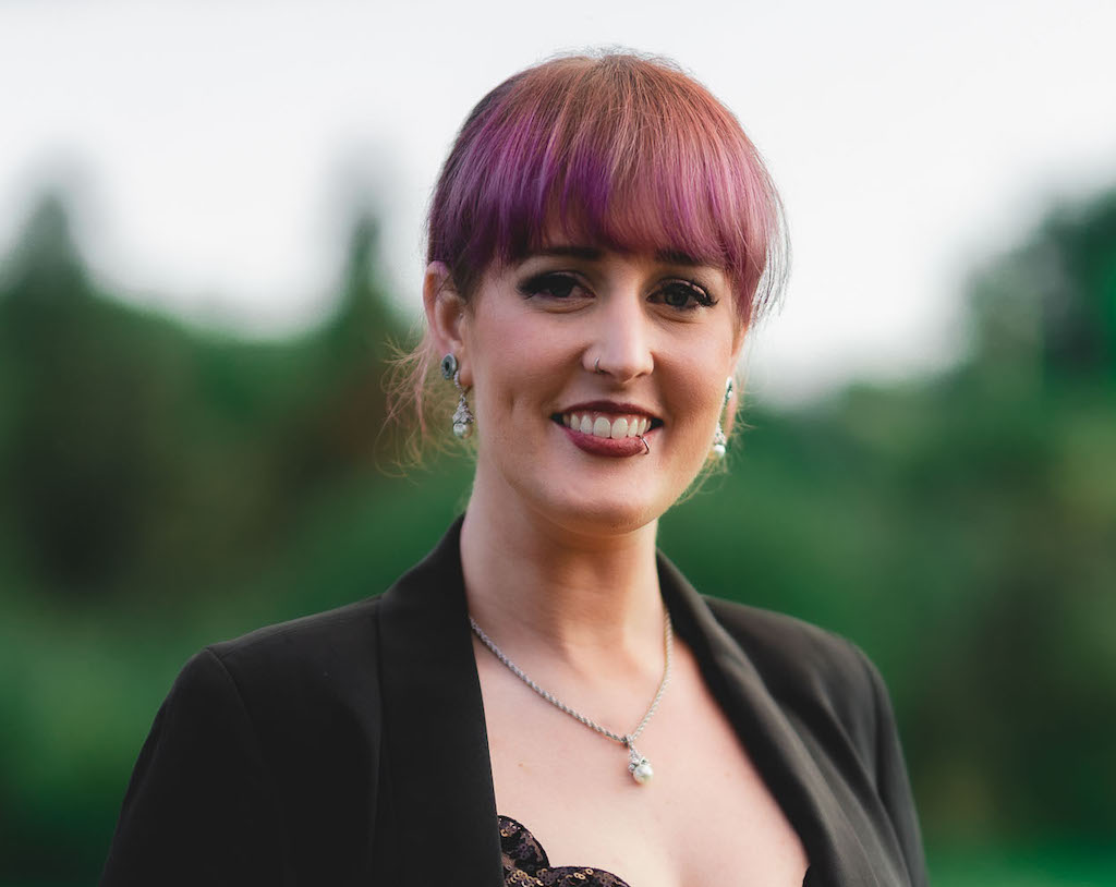 woman with bangs with a black jacket who is smiling and looking at the camera