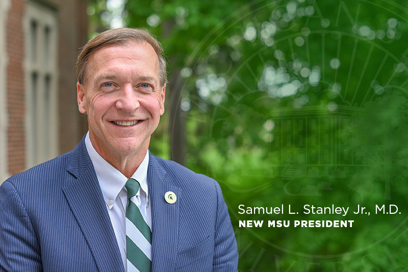 man in blue sports coat and green and white tie smiling,