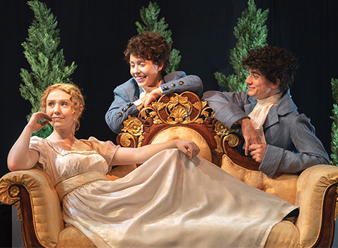 woman wearing a long white dress who's sitting on a couch and looking off into the distance while two men are sitting behind her and smiling at her