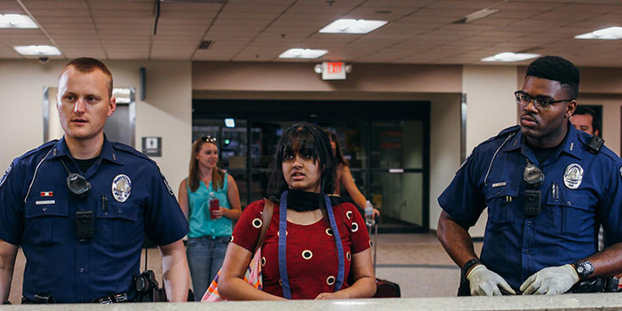 two police officers standing on the sides of a girl, they all look surprised