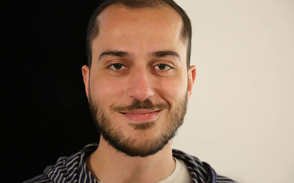 headshot of man with facial hair smiling at camera