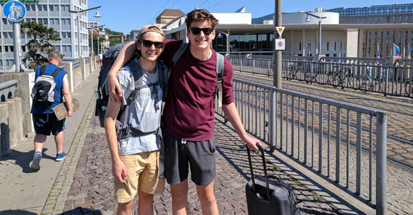 two men posing together with luggage