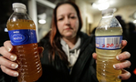 a women holding two water bottles filled with disgusting water