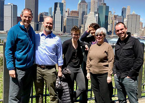 Group of five people standing in front of a city skyline