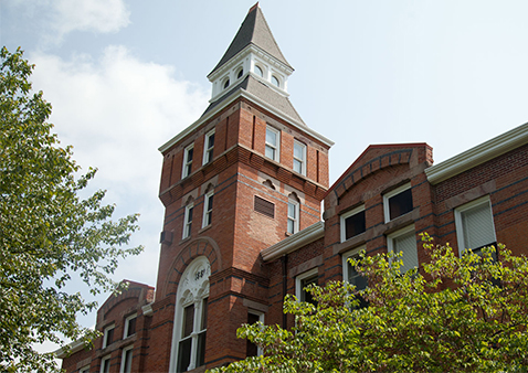 brick building surrounded by trees with green leaves