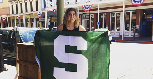 Blonde girl with curly hair holding a green Spartan flag