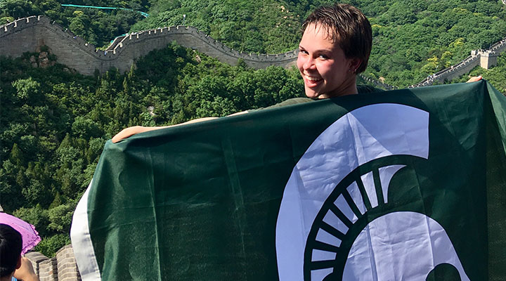 a girl on the wall on china holding a MSU flag