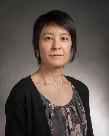 portrait of a woman with short, black hair. she is wearing a floral top and black cardigan