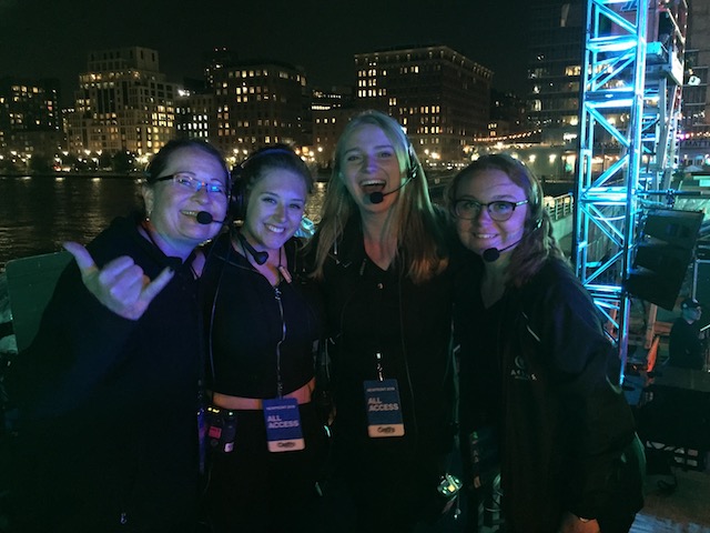 group of four woman backstage in black clothing and headpieces