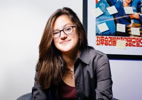 woman with dark brown hair and glasses sitting in an armchair