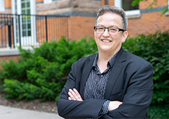 a women in a grey blazer with a black button down wearing glasses