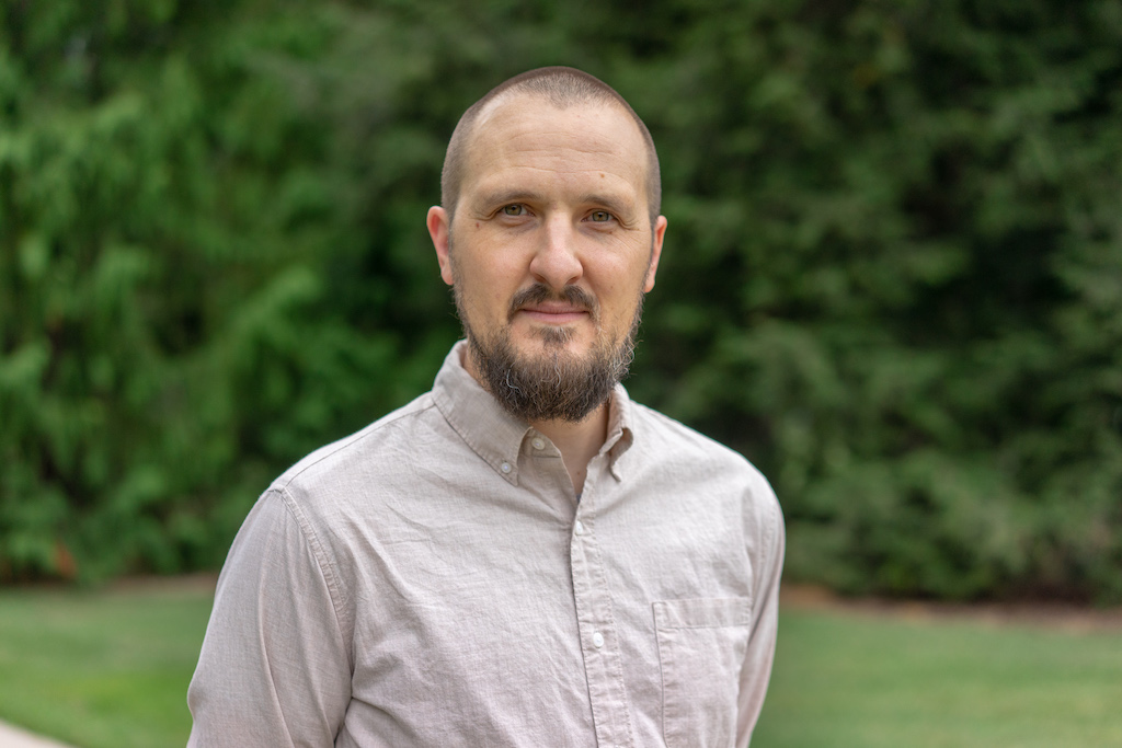 a man with a beard wearing a tan button down