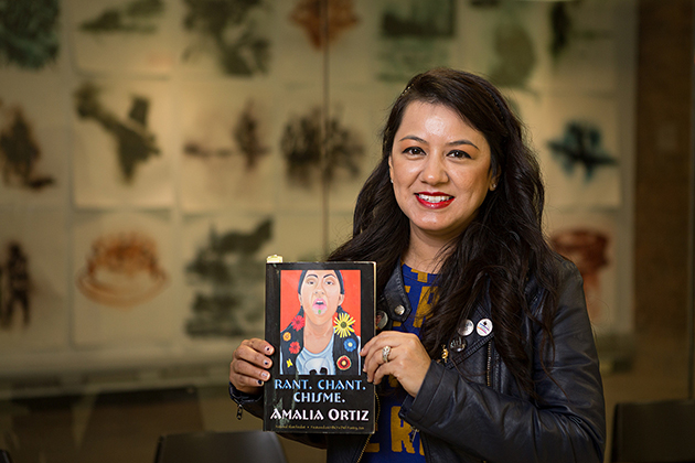 Photo of a woman with dark hair smiling at the camera holding her book