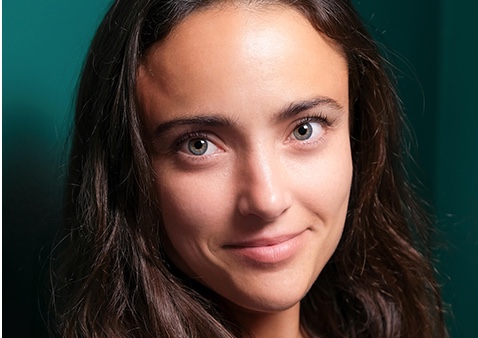 a women with long dark hair wearing a floral shirt with a blue blazer