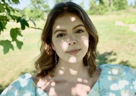 a girl with short light brown hair wearing a light blue floral dress