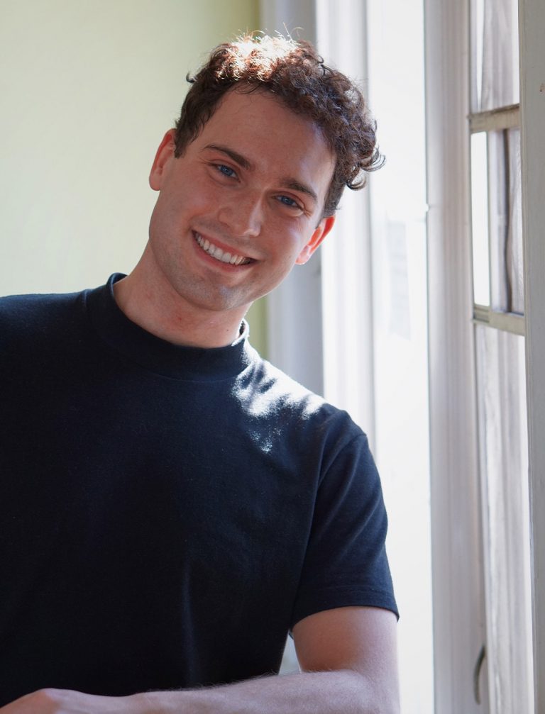 man wearing a black t-shirt smiling directly at the camera