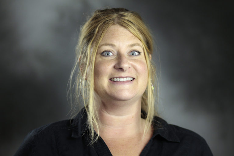 Headshot of a woman with blonde hair in a ponytail wearing a black shirt. 