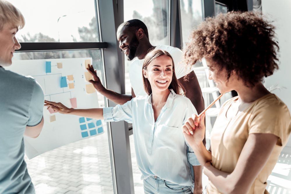 Photo of four people collaborating around a poster with sticky notes.