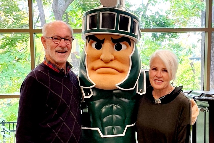 Two people (a man and a woman) standing with Sparty.