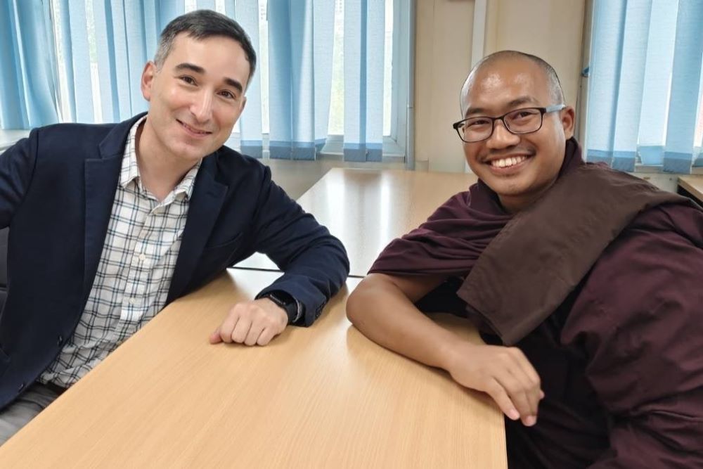 Two men sit across from each other at a table.