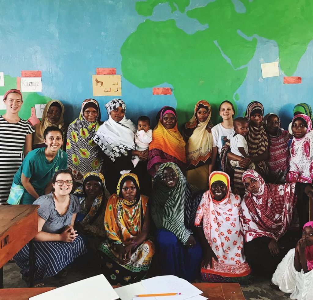 Photo of group of women standing in front of a world map