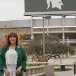 a women in green robes standing in front of the spartan stadium