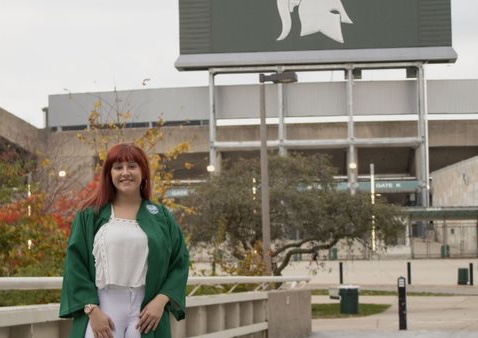 a women in green robes standing in front of the spartan stadium