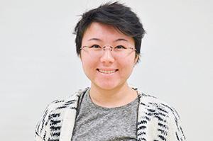 woman wearing glasses wearing a gray shirt smiling at the camera