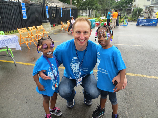 a man smiling with two kids on both sides, they are all wearing matching t-shirts