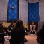 group of people sitting in a circle in a room with notebooks in front of them