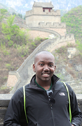 a man wearing a black goat standing on the great wall of china 