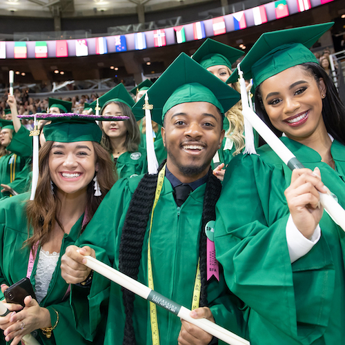 photo of msu students in caps and gowns smiling and holding their diplomas