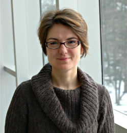 a women with short brown hair wearing glasses and a brown sweater