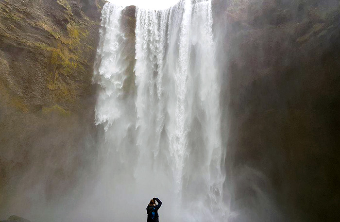 Hannah Robar pointing her camera at a large waterfall