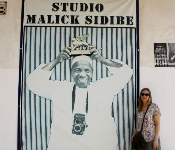 blonde woman standing in front of a mural at Malick Sidibé's studio in Mali