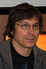 a man wearing glasses and a black shirt with a grey jacket 
