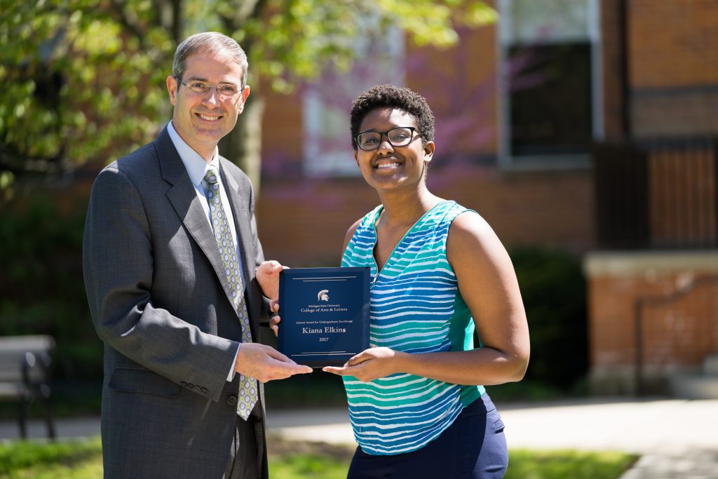 woman accepting award from the college of arts & letters dean
