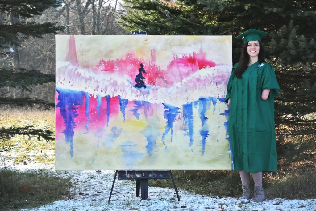 a girl in a green cap and gown standing next to a painting