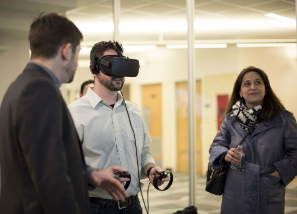 image of a man using a VR headset with two bystanders watching