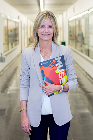 blonde woman posing in hallway of kresge art center holding muses magazine