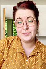 a women with short red hair wearing glasses and a yellow shirt 