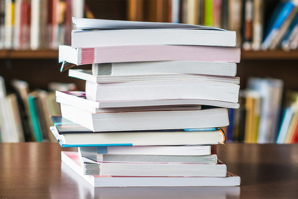 pile of books stacked on top of a wooden table