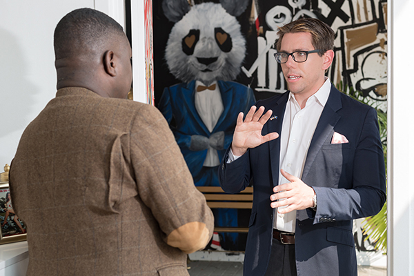 man talking with another man in front of a panda drawing