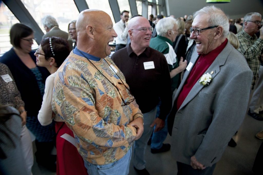 Three men standing near each other talking and laughing