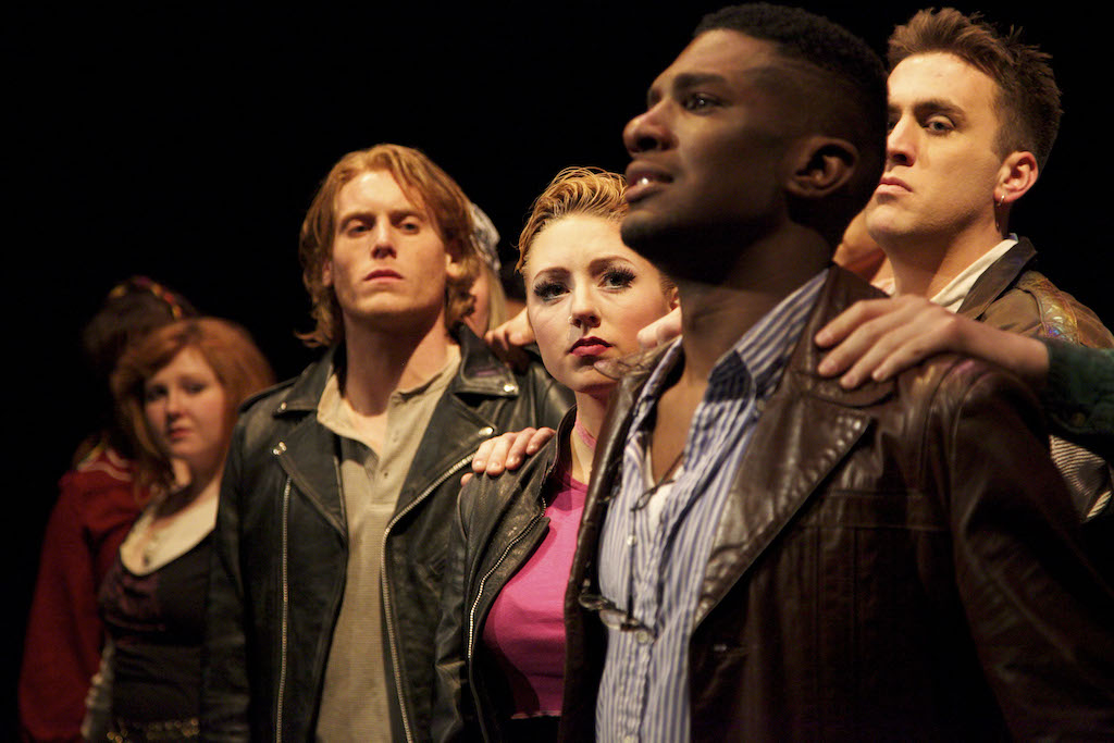 group of individuals who are wearing leather jackets looking at one another