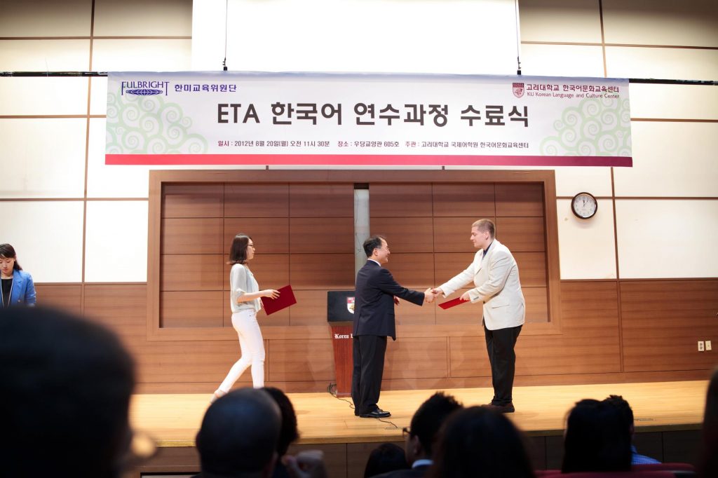 Man in white coat accepting an award on stage