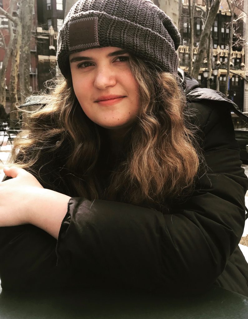 portrait of a girl with brown hair wearing a beanie and a black coat